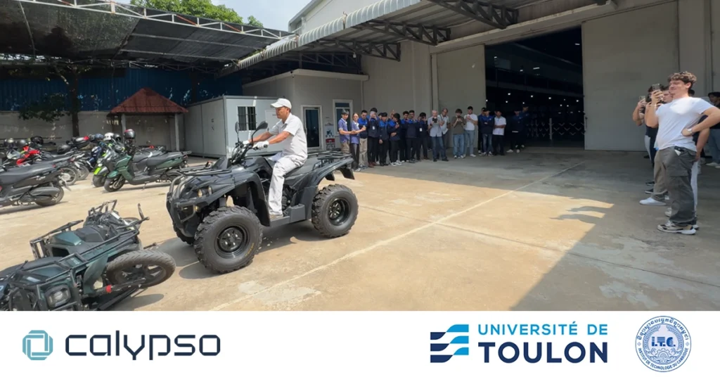 Students, professors, and staff from ITC and Université de Toulon watching a real-time accident simulation where a four-wheel vehicle collides with a Calypso Nijia motorcycle, demonstrating how the Calypso smart system responds during an emergency. Calypso, ITC, and Toulon logos are visible in the image.